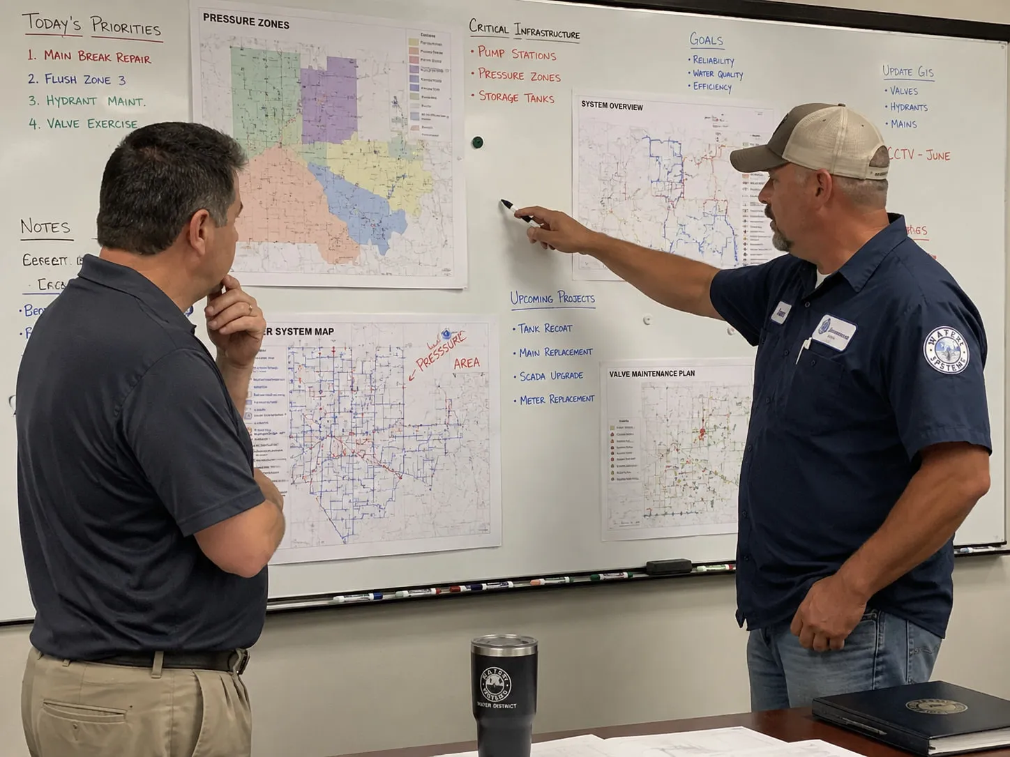 A whiteboard covered in maps, with a General Manager and Operations Superintendent reviewing strategy.